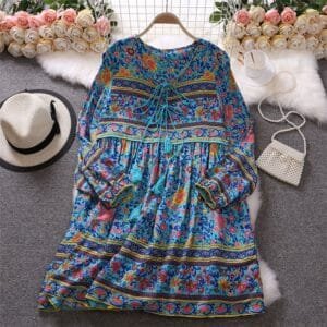 A woman wearing a 38-inch long cotton tunic with vibrant floral patterns and full sleeves, featuring a tassel tie