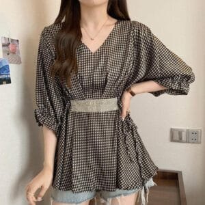 A stylish woman wearing a long houndstooth drop shoulder tunic with a sparkling belt,